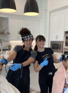 Two Louse Calls technicians in black uniforms smiling together.