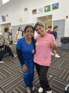 Two smiling Louse Calls team members wearing blue and pink uniforms